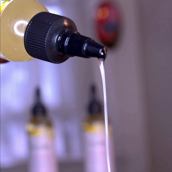 Black woman with textured 4b 4c natural hair pouring all natural growth oil into her hand and in her hair
