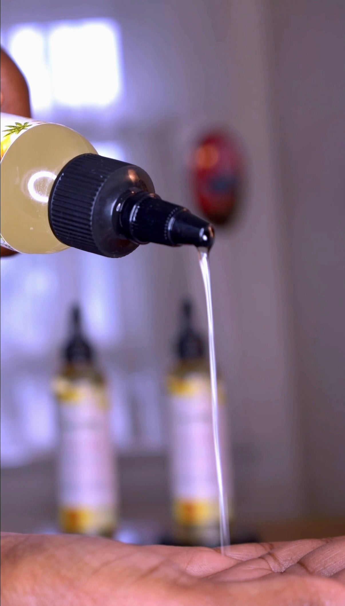 Black woman with textured 4b 4c natural hair pouring all natural growth oil into her hand and in her hair